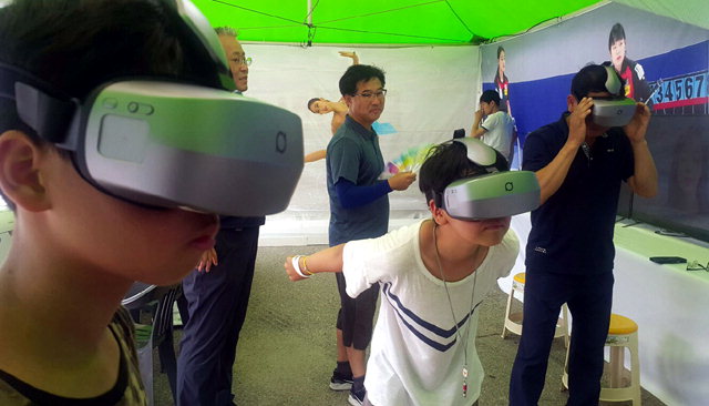 ▲ 21일 인제 바퀴축제장에 마련된 동계올림픽 홍보부스에서 주민과 관광객들이 가상현실(VR) 기기를 활용한 동계스포츠 체험을 하고 있다.