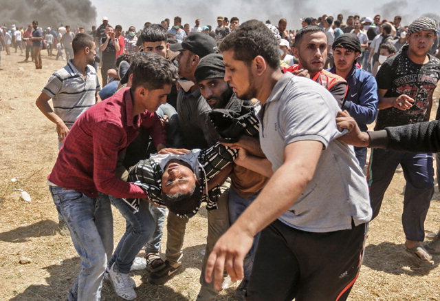 ▲ 이스라엘 주재 미국대사관이 예루살렘으로 이전한 14일(현지시간) 팔레스타인 자치령인 가자지구에서 대규모 항의시위가 벌어진 가운데, 팔레스타인 시위대가 부상한 주민을 옮기고 있다.