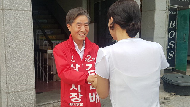 ▲ 김인배(한국당) 후보가 17일 중앙시장 5일장터에서 시민에게 자신에게 지지를 호소하고 있다.