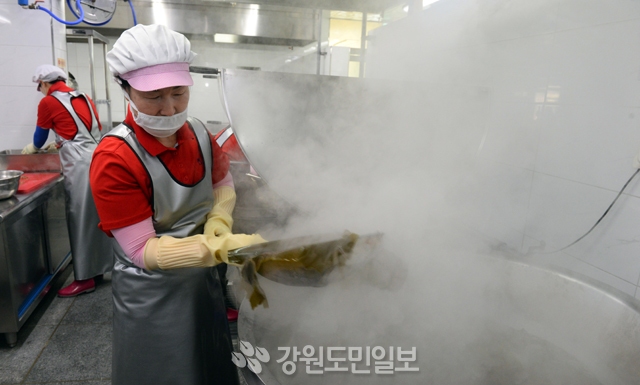 ▲ 16일 춘천의 한 초등학교 급식실에서 조리사가 420명분의 식사를 준비하기 위해 뜨거운 대형 가마솥 앞에서 일하고 있다.  김명준