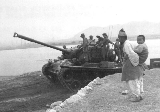 ▲ 6·25한국전쟁 기간인 1951년 4월 4일 춘천 근교 소양강변에서 손자를 업은 한 할아버지가 유엔군 탱크를 지켜보고 있다.  출처 NARA