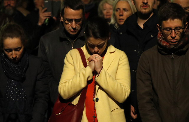 ▲ People pray as Notre Dame cathedral is burning in Paris, Monday, April 15, 2019. A catastrophic fire engulfed the upper reaches of Paris‘ soaring Notre Dame Cathedral as it was undergoing renovations Monday, threatening one of the greatest architectural treasures of the Western world as tourists and Parisians looked on aghast from the streets below. (AP Photo/Christophe Ena)&#10;&#10;&#10;&#10;<All rights reserved by Yonhap News Agency>