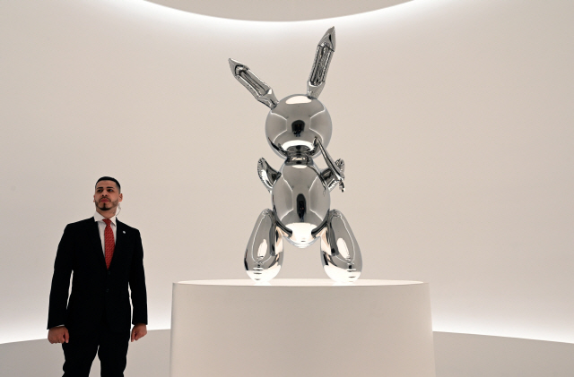 ▲ (FILES) In this file photo taken on May 3, 2019 a security guard stands next to Jeff Koons‘ “Rabbit” from the Masterpieces from The Collection of S.I. Newhouse at Christie’s New York press preview, as  part of Christie‘s Post-War and Contemporary Art evening sale. - Jeff Koons’ “Rabbit” sculpture sold at auction at Christie‘s on May 15, 2019 for $91.1 million, breaking the record for a work by a living artist. (Photo by TIMOTHY A. CLARY / AFP) / RESTRICTED TO EDITORIAL USE - MANDATORY MENTION OF THE ARTIST UPON PUBLICATION - TO ILLUSTRATE THE EVENT AS SPECIFIED IN THE CAPTION    <All rights reserved by Yonhap News Agency>
