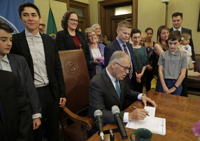 ▲ Katrina Spade, upper left, the founder and CEO of Recompose, a company that hopes to use composting as an alternative to burying or cremating human remains, looks on Tuesday, May 21, 2019, as Washington Gov. Jay Inslee, center, signs a bill into law at the Capitol in Olympia, Wash., that allows licensed facilities to offer “natural organic reduction,” which turns a body, mixed with substances such as wood chips and straw, into soil in a span of several weeks. The law makes Washington the first state in the U.S. to approve composting as an alternative to burying or cremating human remains. (AP Photo/Ted S. Warren)    <All rights reserved by Yonhap News Agency>
