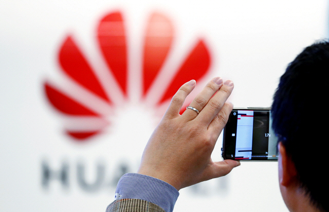 ▲ FILE PHOTO: A man takes a picture of a Huawei logo at the Huawei European Cybersecurity Center in Brussels, Belgium, May 21, 2019. REUTERS/Francois Lenoir/File Photo    <All rights reserved by Yonhap News Agency>