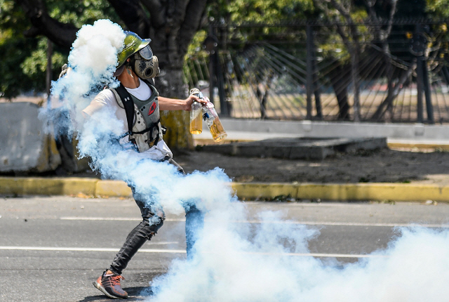 ▲ TOPSHOT - An anti-government protester throws Molotov cocktails during clashes with security forces in the surroundings of La Carlota military base in Caracas during the commemoration of May Day on May 1, 2019 after a day of violent clashes on the streets of the capital spurred by Venezuela‘s opposition leader Juan Guaido’s call on the military to rise up against President Nicolas Maduro. - Guaido called for a massive May Day protest to increase the pressure on President Maduro. (Photo by Matias DELACROIX / AFP)    <All rights reserved by Yonhap News Agency>