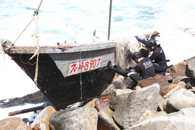 ▲ 12일 오전 10시 37분쯤 고성군 거진1리 해안가에서 발견된 북한 소형목선 인양을 위해 해양경찰구조대가 투입,작업을 하고 있다. 이동명