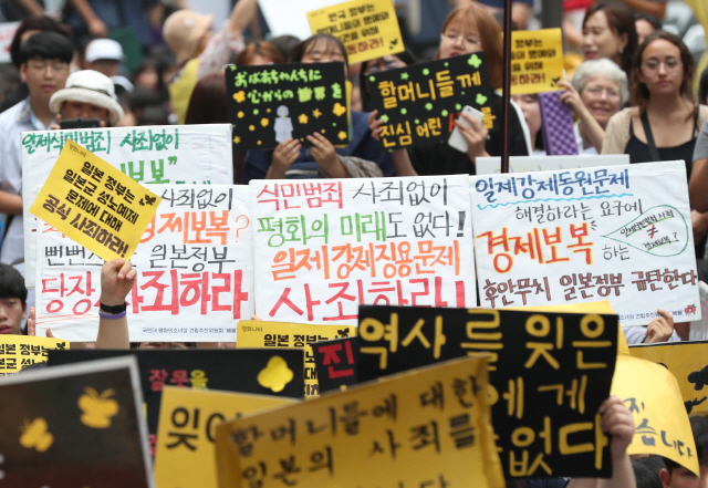 17일 서울 종로구 옛 일본대사관 앞에서 열린 제1396차 일본군 성노예제 문제 해결을 위한 정기 수요집회에서 참가자들이 역사 사죄 촉구 및 경제 보복을 규탄하는 피켓을 들고 구호를 외치고 있다.