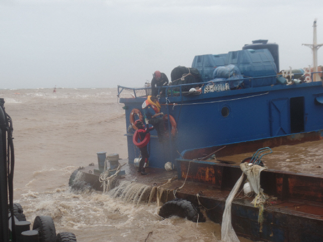 20일 오후 경북 영덕군 강구항에서 집중호우로 불어난 물에 항 내에서 표류하던 바지선 2척을 울진해양경찰서 관계자들이 구조하고 있다. 