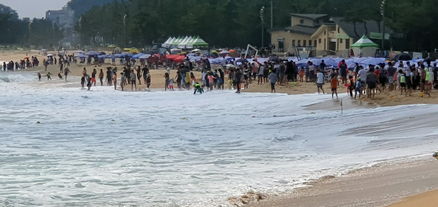 폐장을 하루 앞둔 17일 속초해수욕장을 찾은 피서객들이 동해안의 너울성 파도로 수영이 금지되자 바닷가에서 아쉬움을 달래고 있다. 