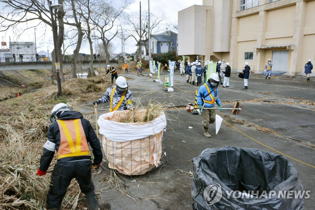 ▲ 2017년 12월 25일 후쿠시마현 후타바마치에서 방사성 물질 오염 제거 작업이 진행 중이다. 작업자들이 풀 등을 베어 자루에 담고 있다.