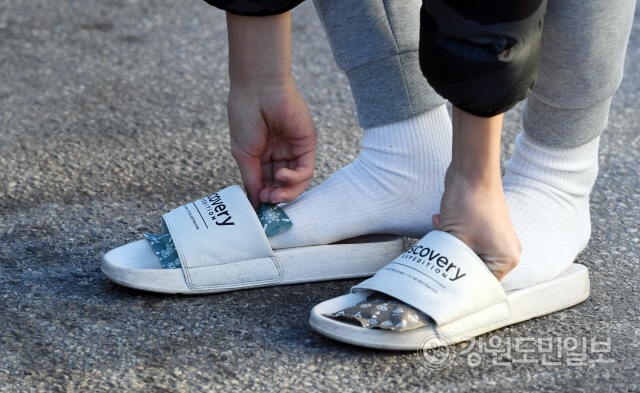 ▲ 수능 한파가 몰아친 14일 시험장인 춘천고에서 수험생을 응원 나온 한 재학생이 발에 핫팩을 대고 있다.  최유진