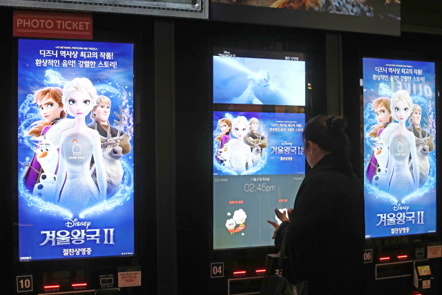 ▲ 디즈니 애니메이션 &lsquo;겨울왕국2&rsquo; 개봉 첫날인 21일 오후 서울 시내 한 영화관 전자매표소에서 시민이 영화표를 발권하고 있다. 영화진흥위원회 영화관입장권 통합전산망에 따르면 &lsquo;겨울왕국2&rsquo;는 이날 오전 6시 기준 국내 개봉 애니메이션 사상 처음으로 예매량 110만장(예매율 93%)을 넘어섰다. 2019.11.21