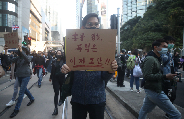 ▲ 8일 오후 홍콩 빅토리아공원에서 도심 센트럴로 향하는 대규모 행진 대열에 한 시위 참가자가 &ldquo;홍콩 경찰, 폭력은 이제 그만&rdquo;이라고 한글로 쓴 피켓을 들고 있다. 2019.12.8