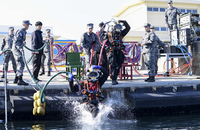 ▲ 해군 1함대 구조작전중대와 동해해경청 해양특수구조대의 합동 잠수훈련이 14일 동해 군항에서 열려 표면공급 잠수장비를 착용한 대원이 바다에 뛰어들고 있다.