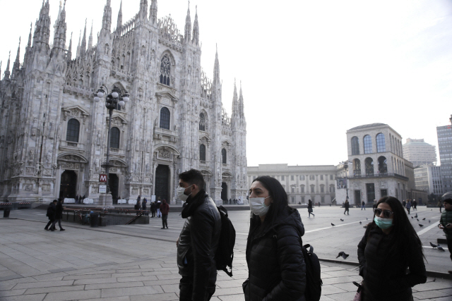 ▲ 23일(현지시간) 이탈리아 북부 밀라노에서 신종 코로나바이러스 감염증(코로나19) 우려로 마스크를 착용한 사람들이 고딕 대성당인 &lsquo;두오모&rsquo; 앞을 지나가고 있다.