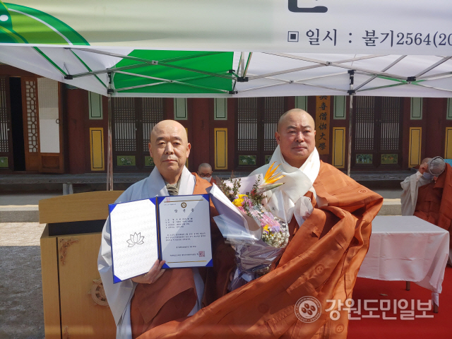 ▲ 신흥사 차기 주지후보로 추대된 지혜 스님이 전 주지인 우송 스님(오른쪽)으로부터 축하 꽃다발을 받았다.
