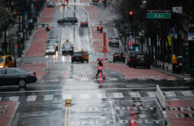 ▲ A person crosses 42th street as rain falls on March 28, 2020 in New York City. - US President Donald Trump said on March 28, 2020 that he‘s considering a short-term quarantine of New York state, New Jersey, and parts of Connecticut. (Photo by Kena Betancur / AFP)