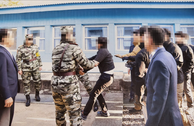 ▲ 통일부는 지난 2019년 11월 판문점에서 탈북어민 2명을 북한으로 송환하던 당시 촬영한 사진을 12일 공개했다. 당시 정부는 북한 선원 2명이 동료 16명을 살해하고 탈북해 귀순 의사를 밝혔으나 판문점을 통해 북한으로 추방했다. 사진은 탈북어민이 몸부림치며 북송을 거부하는 모습. [통일부 제공]