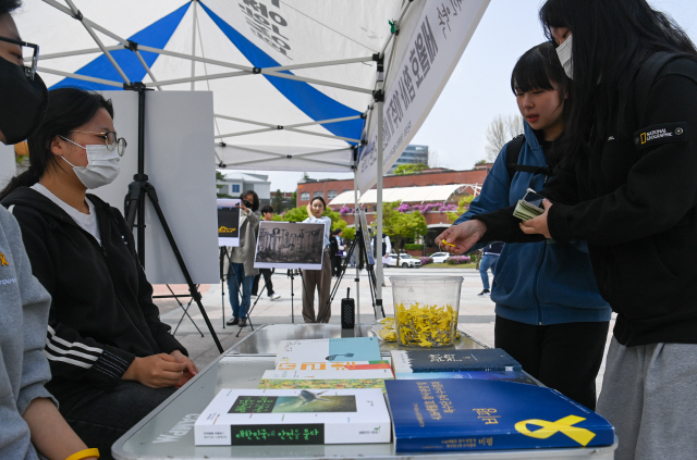 ▲ 세월호 참사 10주기인 16일 강원대학교 춘천캠퍼스에 마련된 세월호 참사 추모 공간에서 학생들이 노란리본을 받고 있다. 유희태