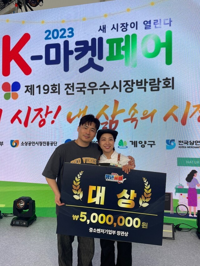 ▲ 2023년 중소벤처기업부와 소상공인진흥공단이 주관하는 ‘전통시장 청년상인 요리대결-청년불패’에서 대상을 수상한 황은지 대표와 그의 남편이 기념사진을 촬영하고 있다.