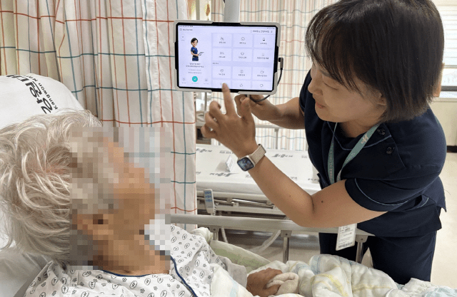 ▲ 강원대학교병원이 국내 최초로 암 환자 간호를 위한 인공지능(AI) 보조시스템을 도입, 간호사가 환자에게 사용법을 설명하고 있다. 강원대병원 제공
